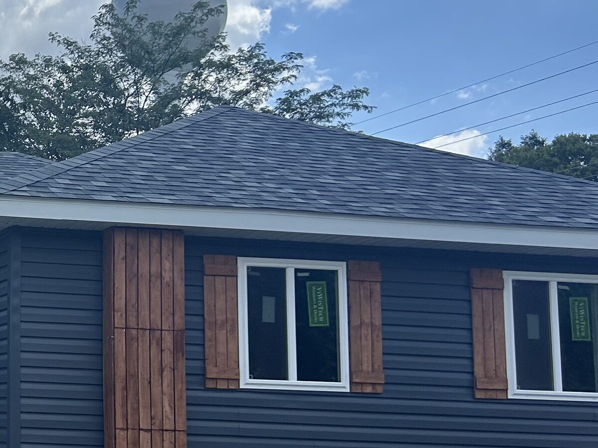Detail of navy lap siding, cedar board-and-batten shutters, and shingle roof by Zerkle Construction